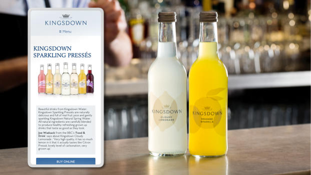 A bar scene with a smartphone showing the Kingsdown Water website next to a selection of KW drinks on the bar.