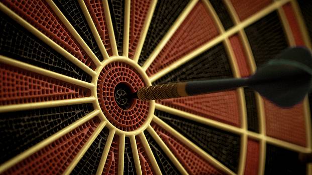 A black dart sticks out of the centre bullseye of a dartboard. Cropped to just show the middle third of the board.